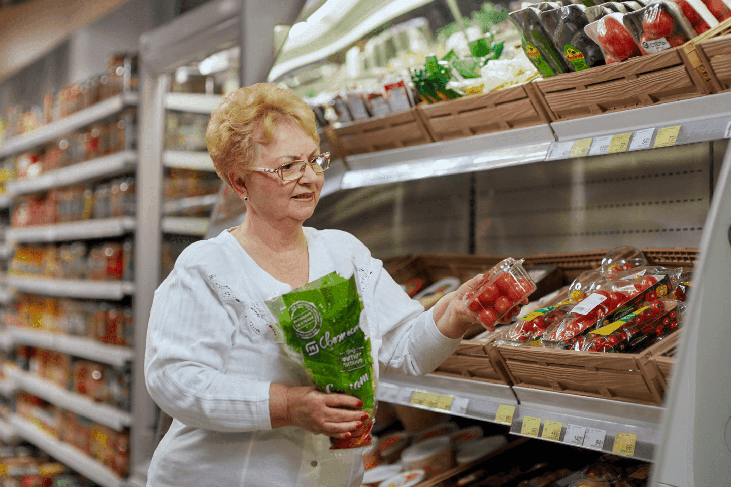 Женщина в магазине выбирает овощи 